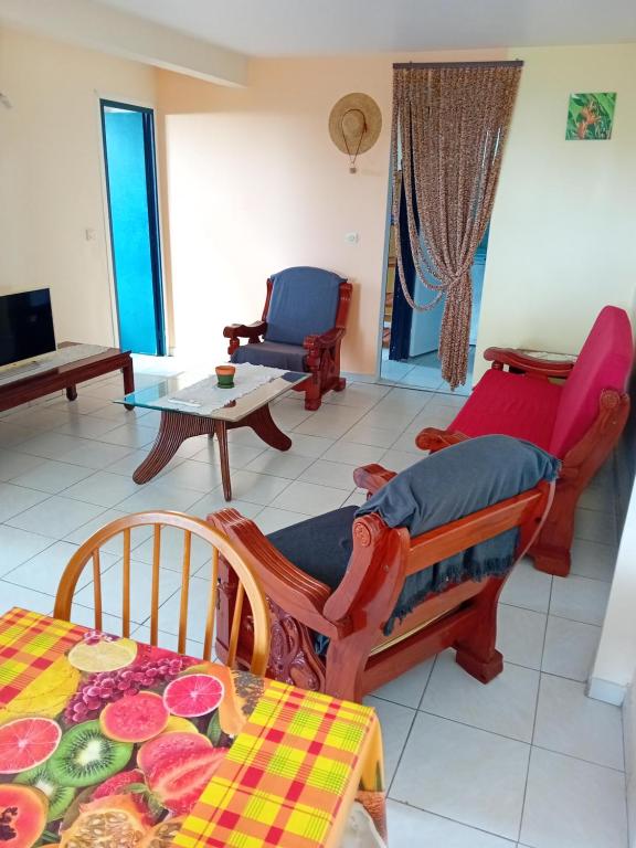 a living room with a table and chairs and a couch at Les palmiers in Le Marin