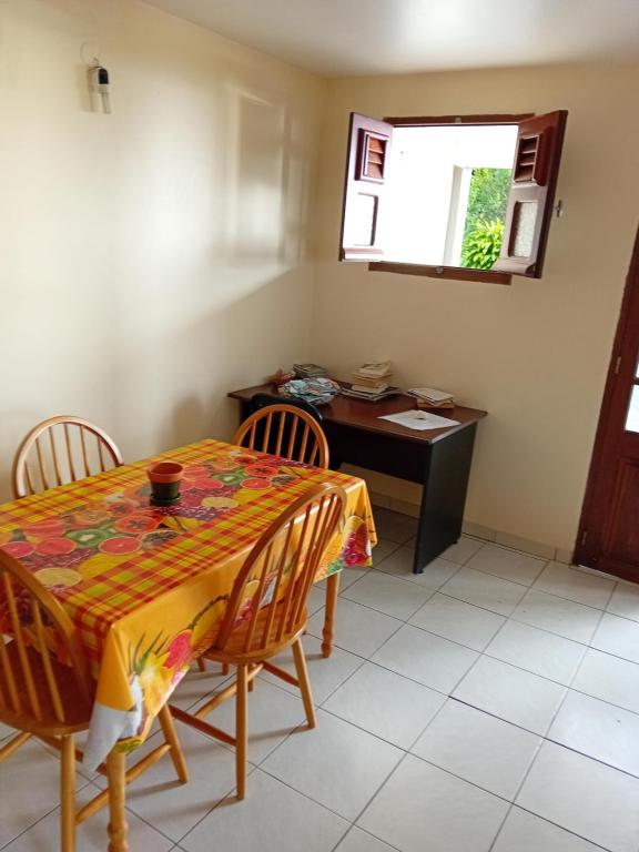 a dining room with a table and chairs and a desk at Les palmiers in Le Marin