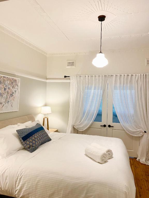 a bedroom with a white bed with white curtains at Katoomba Cottage in Katoomba