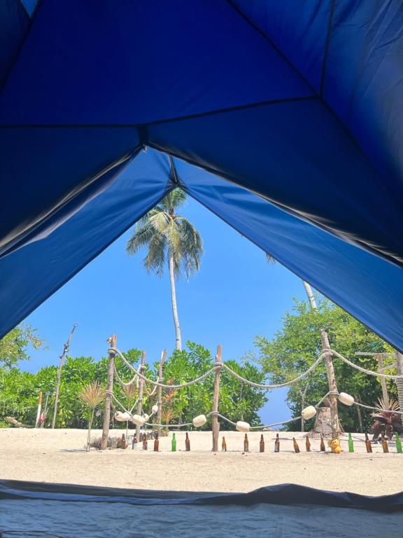 a blue umbrella on a beach with a palm tree at Redang Campstay in Redang Island