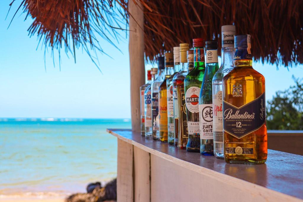 a row of bottles of alcohol sitting on a counter next to the beach at Taboo Milagres in São Miguel dos Milagres