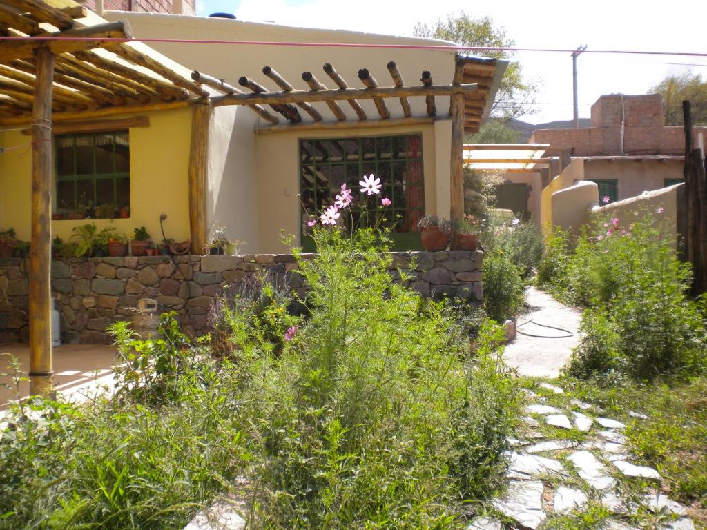 a garden in front of a house with a stone wall at casaglo in Maimará