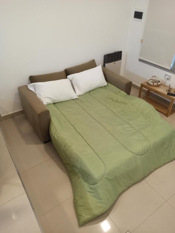 a bed with a green blanket in a room at Departamento Elena 2 in Santa Rosa