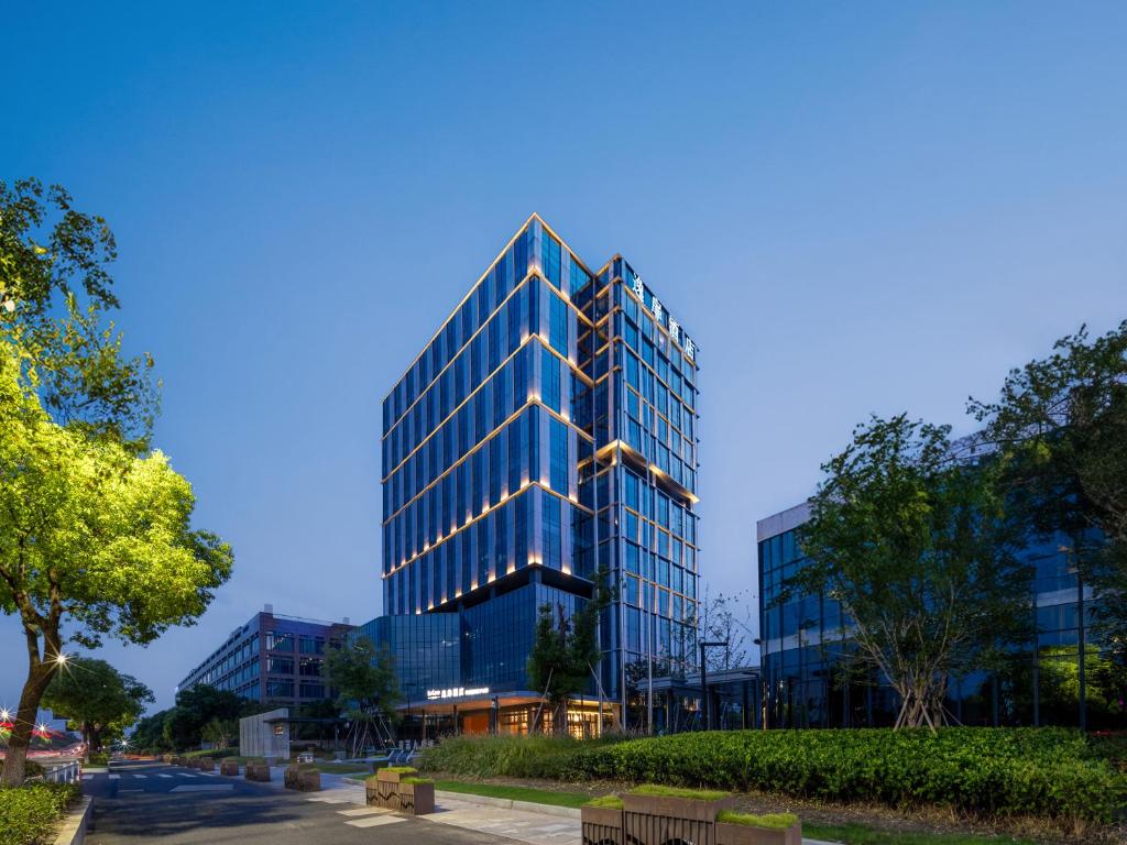 un grand bâtiment en verre éclairé dans l'établissement UrCove by Hyatt Hangzhou Xiaoshan International Airport, à Hangzhou