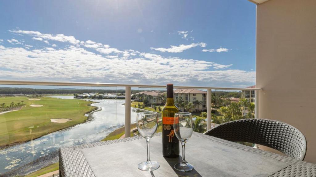 a bottle of wine and two wine glasses on a table at Lovely Studio Apartment Overlooking Golf Course! in Pelican Waters