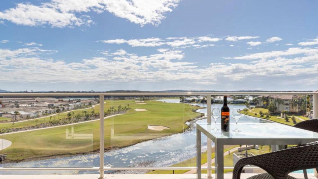 - une vue sur un parcours de golf depuis un balcon avec une bouteille de vin dans l'établissement Spa Apartment - Beautiful Views Of Golf Course!, à Pelican Waters