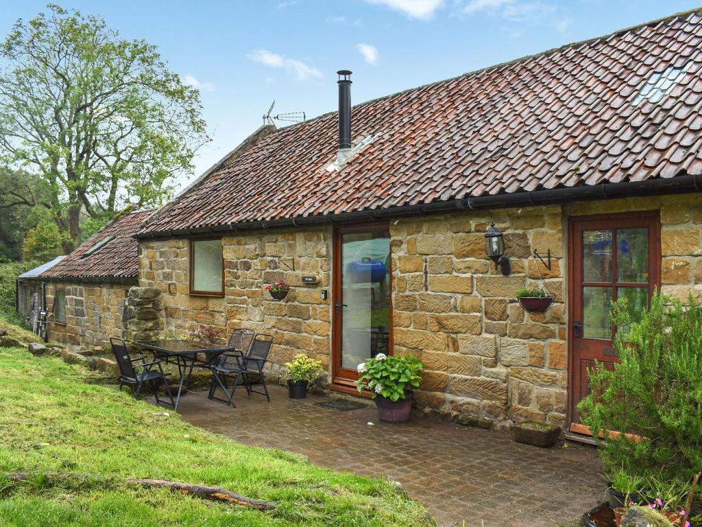 a stone cottage with a table and chairs in front of it at The Byre in Ingleby