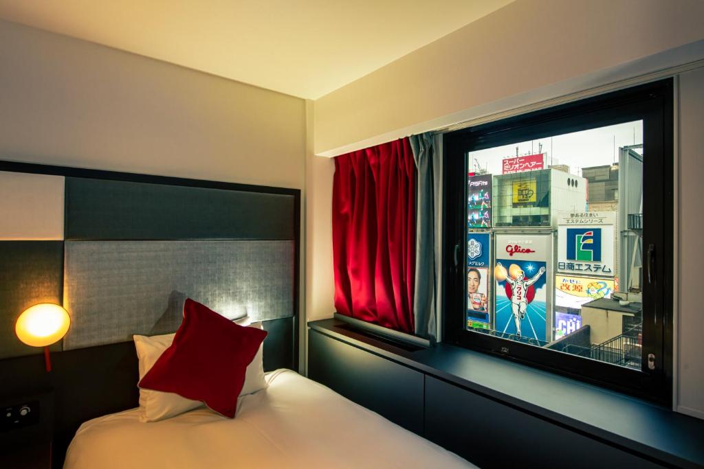 a bedroom with a bed and a window with a television at Cross Hotel Osaka in Osaka
