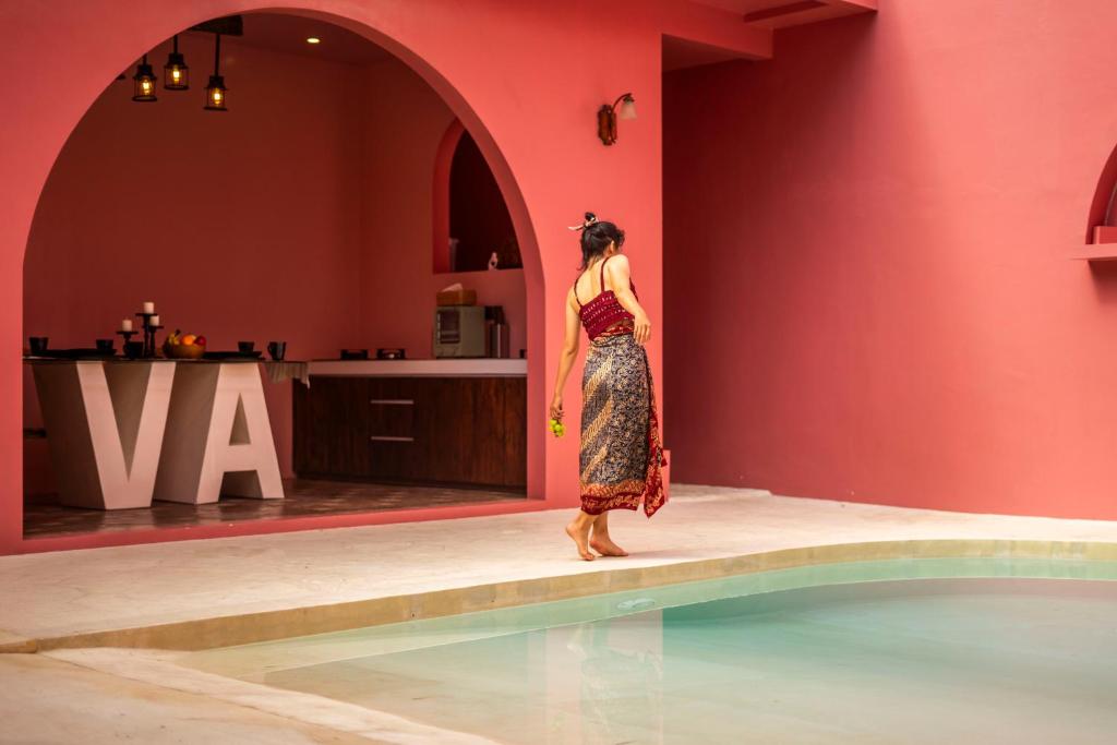 uma mulher de vestido ao lado de uma piscina em VA Villa Jimbaran Bali em Jimbaran