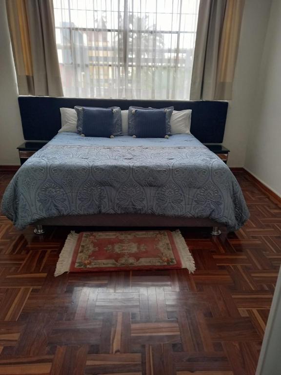 ein Schlafzimmer mit einem Bett und einem Teppich auf einem Holzboden in der Unterkunft Departamento en Pueblo Libre in Lima