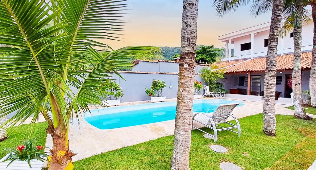 uma villa com piscina e palmeiras em Casa com piscina - Praia do Pernambuco no Guarujá