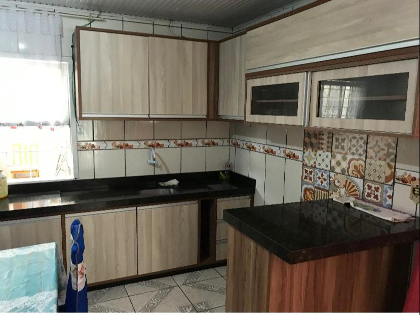 a kitchen with wooden cabinets and a black counter top at Casa praia da cal in Torres