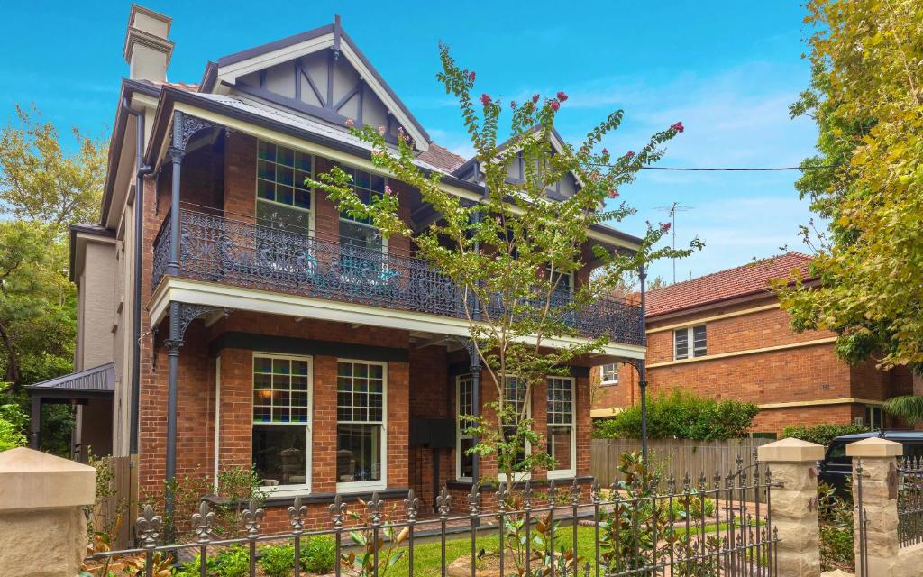 ein Backsteinhaus mit einem Zaun davor in der Unterkunft Dalziel Lodge in Sydney