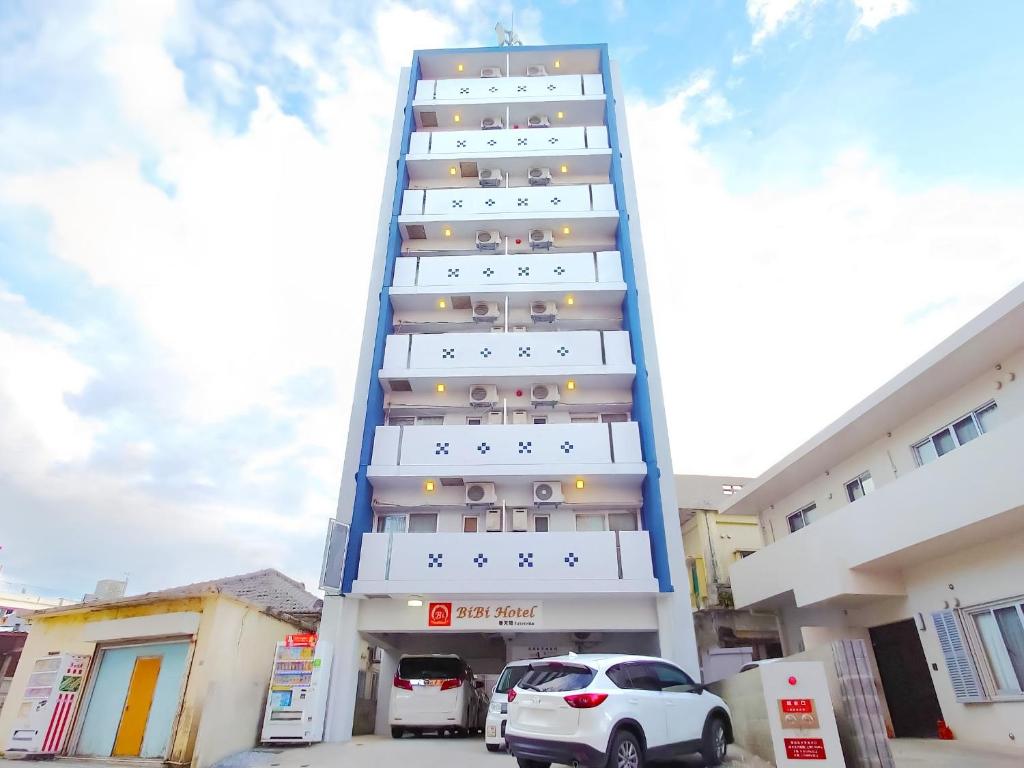 un edificio alto con coches estacionados frente a él en BiBi Hotel FUTENMA, en Ginowan