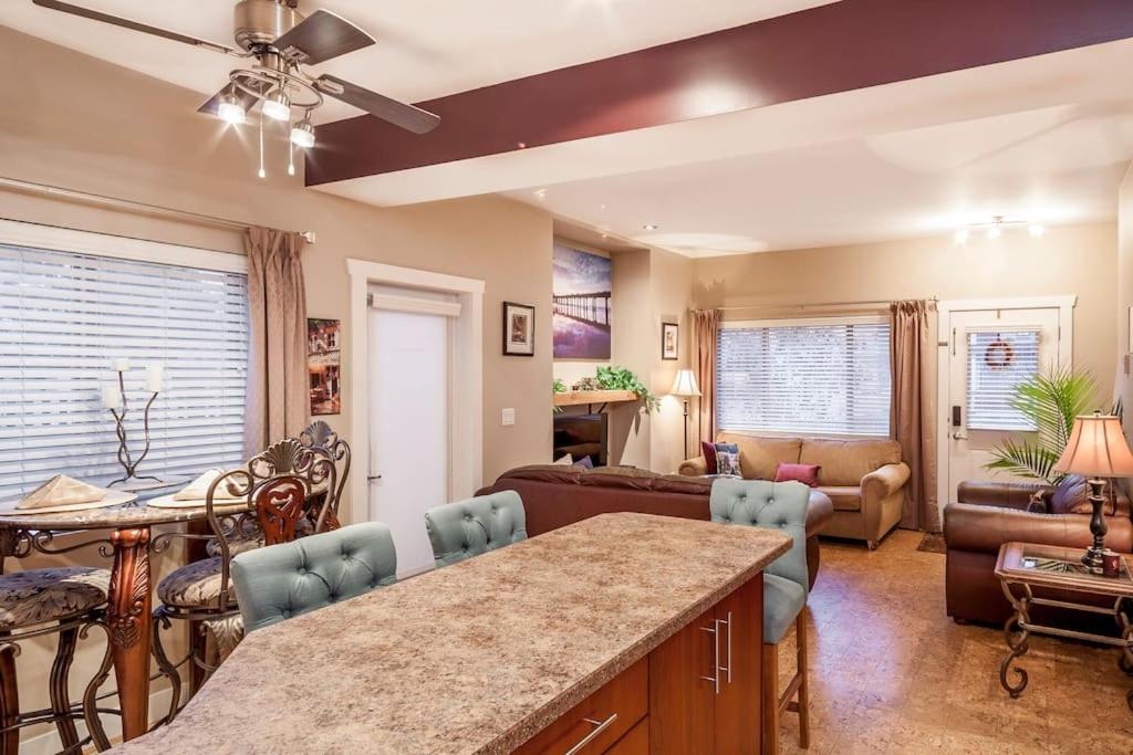 a kitchen and living room with a couch and a table at Peaches & Wine Villa Penticton in Penticton