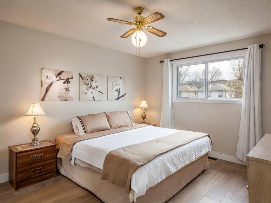 a bedroom with a bed with a ceiling fan and a window at Zena's By The Beach in Penticton