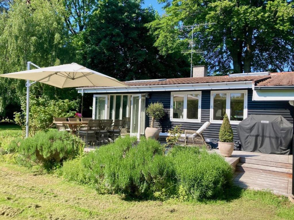 een blauw huis met een paraplu en een houten terras bij Holiday home Hornbæk II in Hornbæk