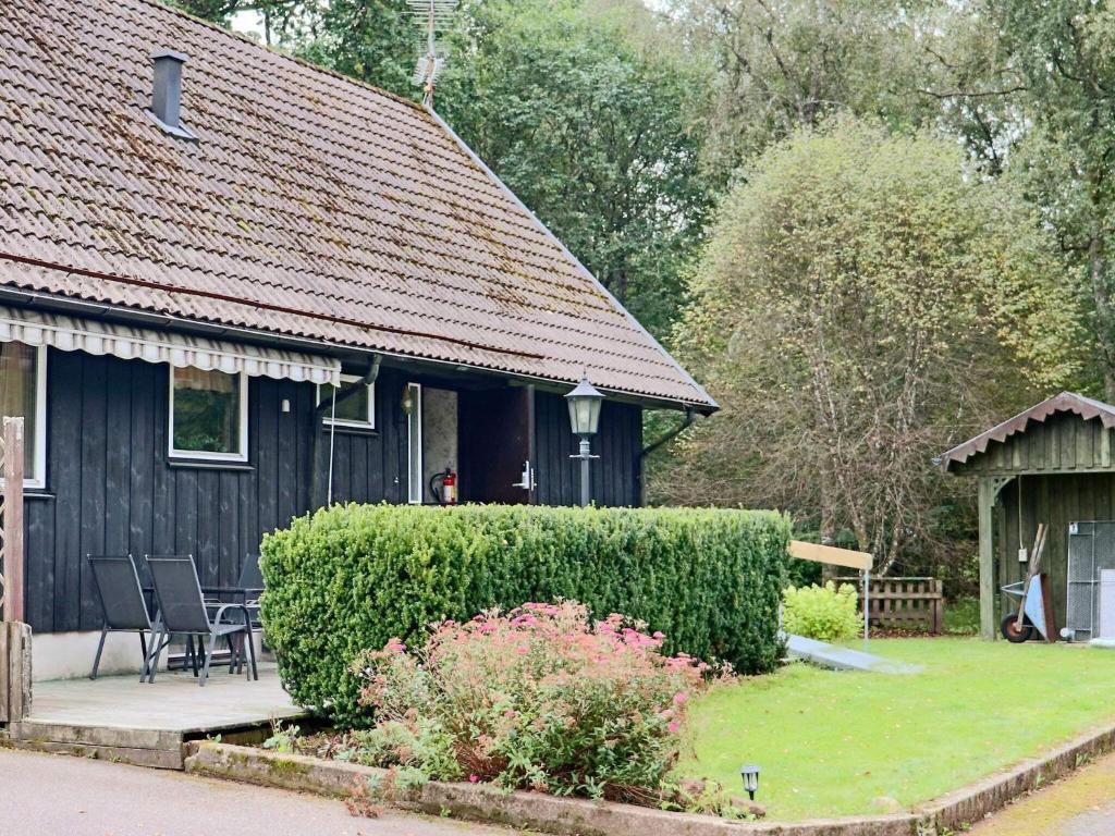 a black house with a table and a chair outside at 4 star holiday home in ULLARED-By Traum in Ullared