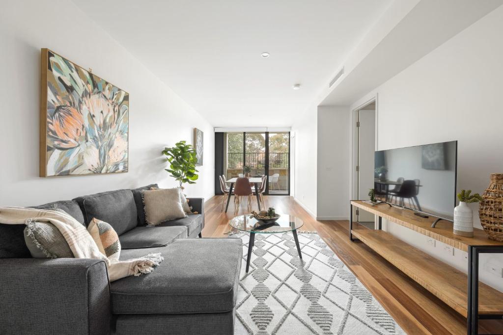 ein Wohnzimmer mit einem Sofa und einem Tisch in der Unterkunft Founders Lane Apartments by Urban Rest in Canberra
