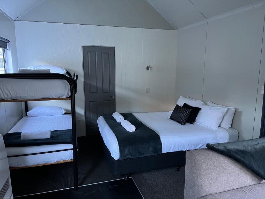 アロータウンにあるHampshire Holiday Parks - Arrowtownのベッド2台と二段ベッド1組が備わる客室です。