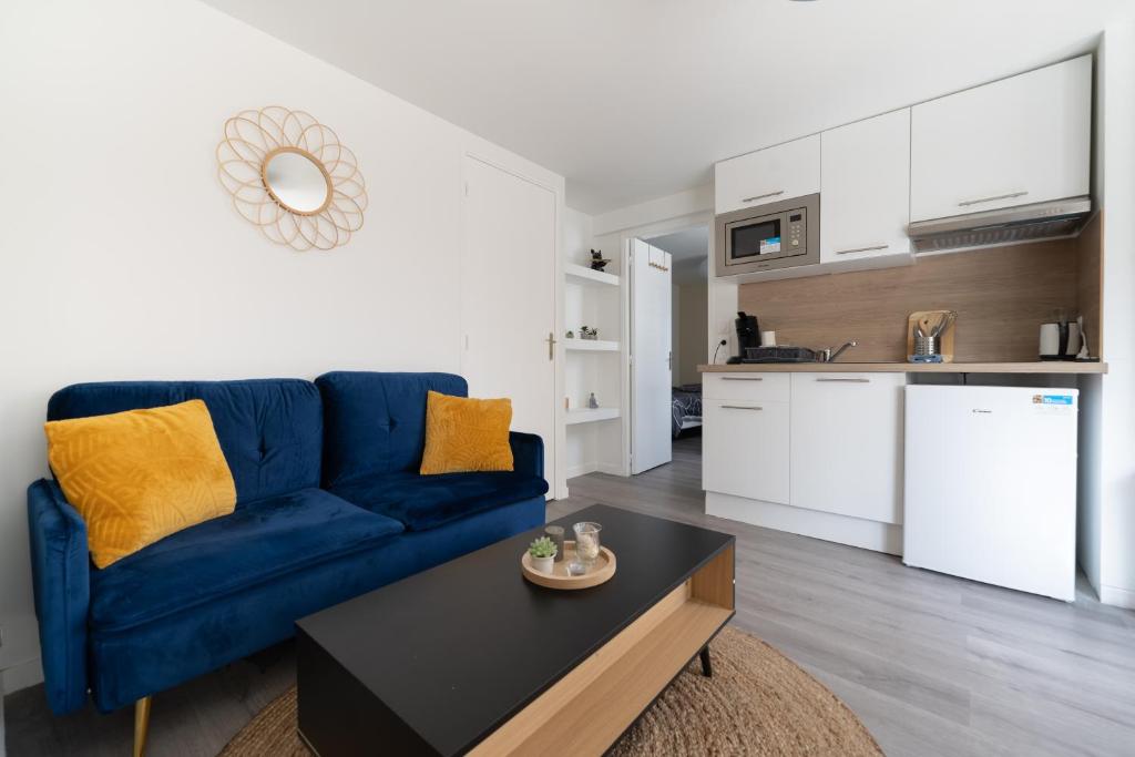 Il comprend un salon avec un canapé bleu et une cuisine. dans l'établissement T2 idéal déplacement pro, entièrement rénové, à Rouen