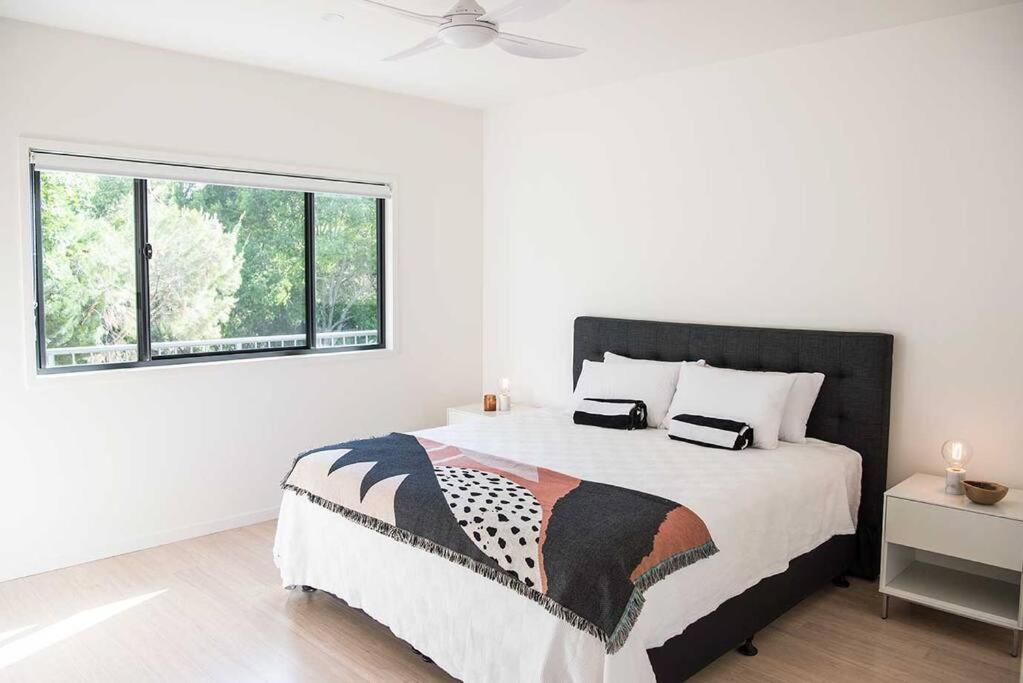 um quarto branco com uma cama grande e uma janela em "Palm Retreat" - Private, Spacious and Bright em Noosa Heads