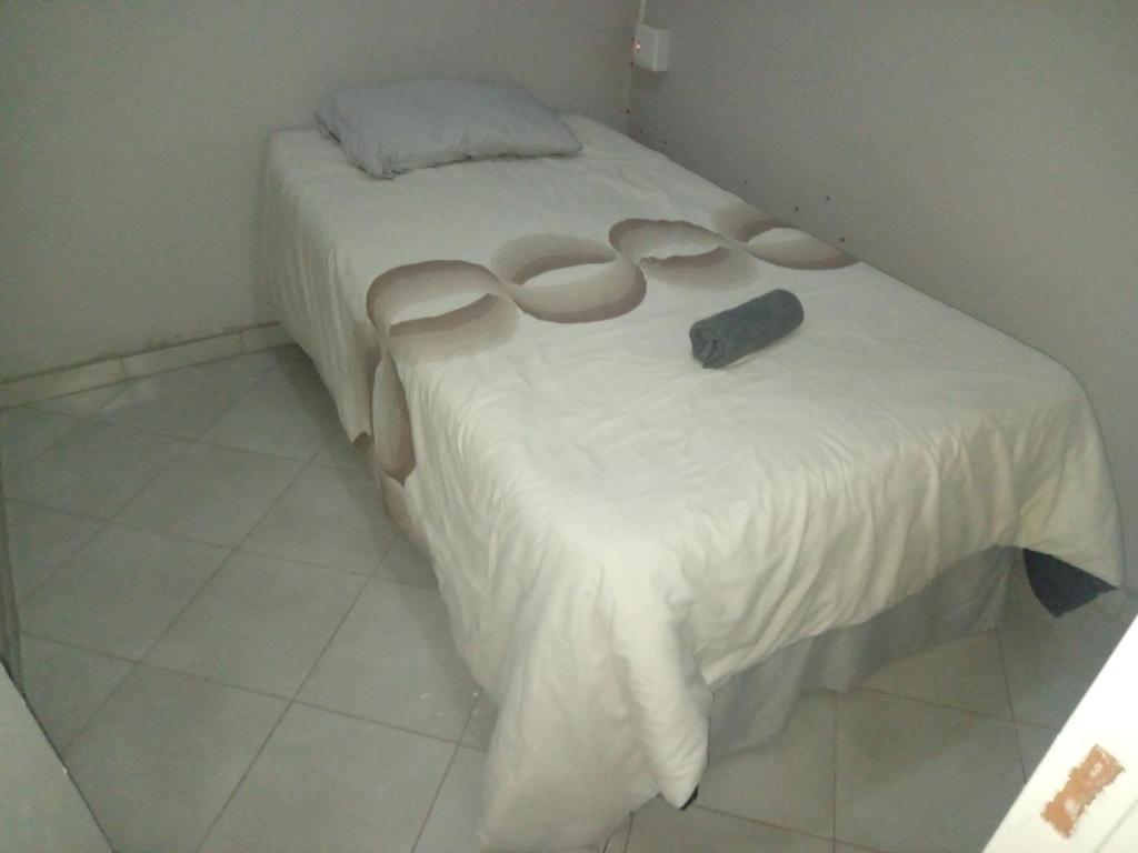 a white bed with a black object on it at Las Palmas Day & Night Guest House in Pretoria