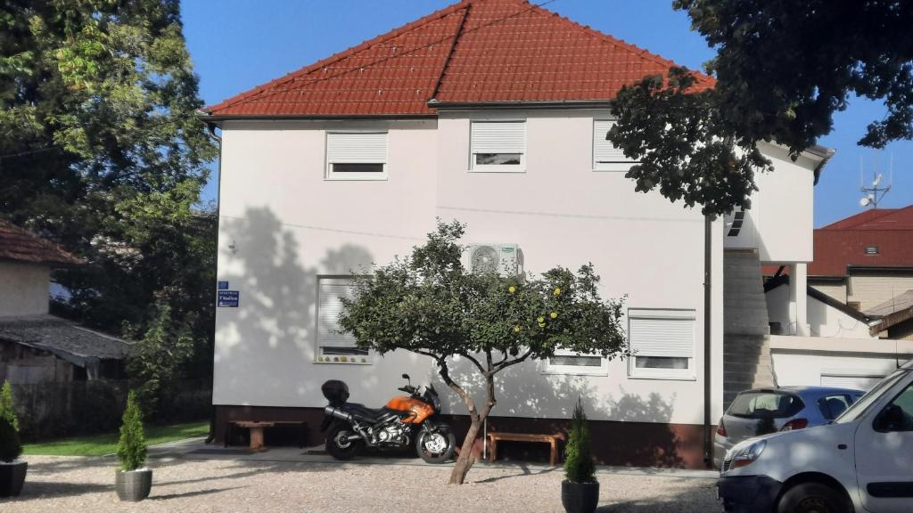une moto garée devant un bâtiment blanc dans l'établissement 7 Kućica, à Livno
