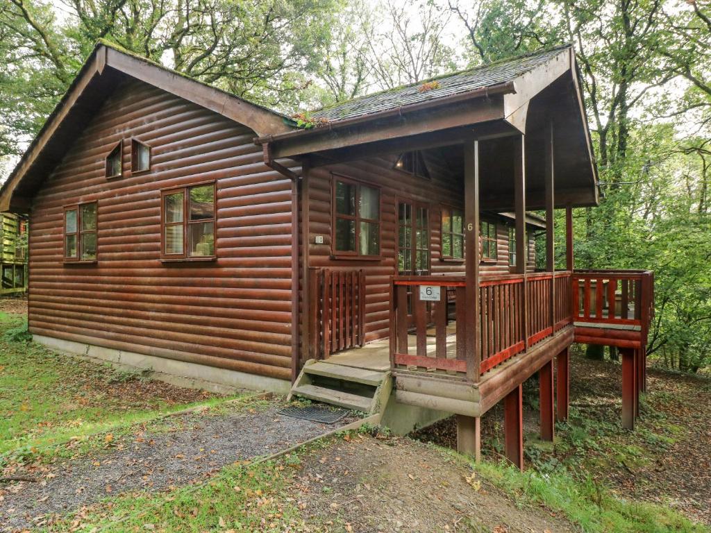 eine Blockhütte im Wald mit einer Veranda in der Unterkunft Acorn Lodge in Mydrim