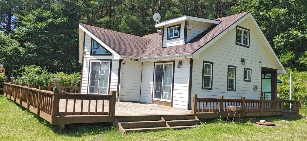 a small white house with a large wooden deck at Songha Village in Jeongseon