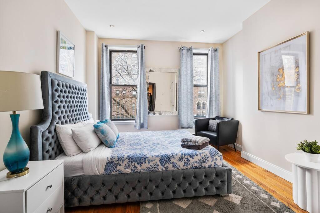 a bedroom with a bed and a chair and windows at Perfect Chic Apartment in Upper West of NYC! in New York