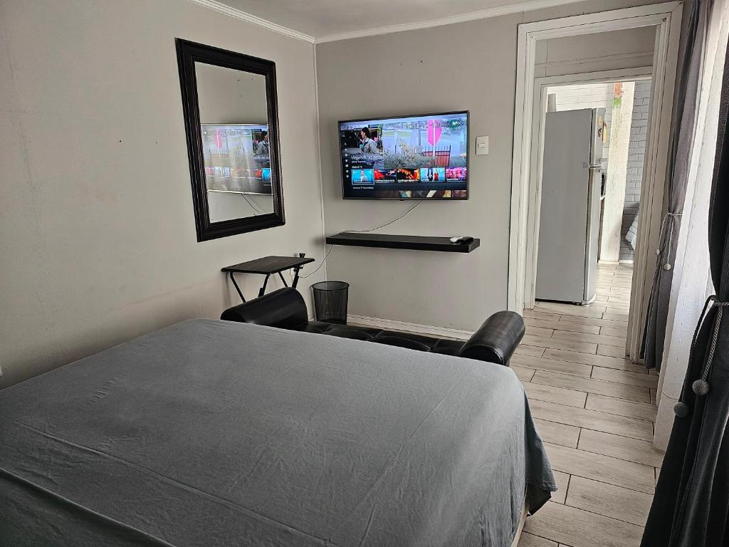1 dormitorio con 1 cama y TV en la pared en Apartamento Interior 2do Piso Casa, 026 Quilicura en Santiago