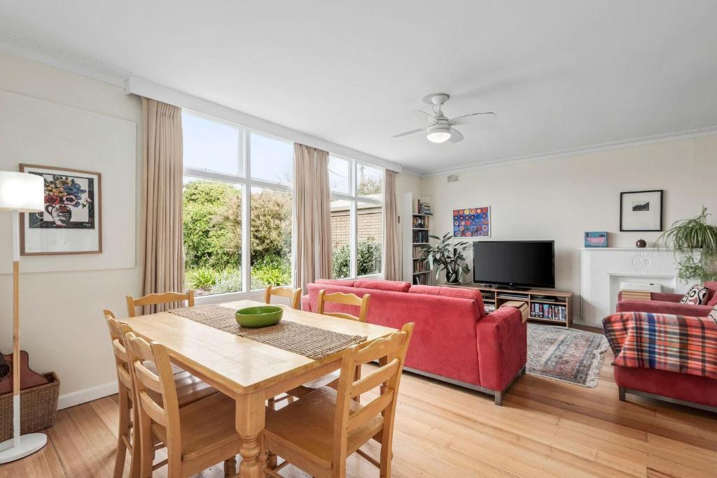 Una sala de estar con una mesa y un sofá rojo. en Beach Bach, en Point Lonsdale