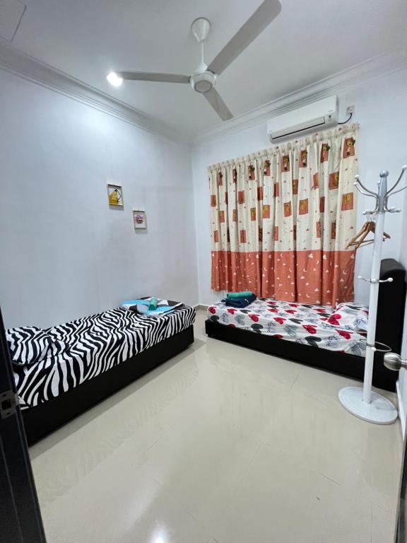 2 camas sentadas en una habitación con cortina en EMPIRE HOMESTAY PAKA ROOM 3, en Paka