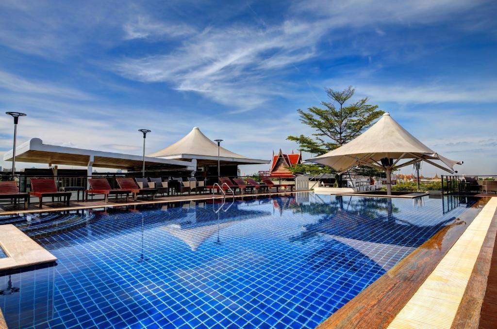 uma grande piscina com cadeiras e guarda-sóis em Dang Derm Khaosan em Banguecoque