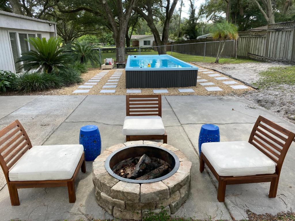 un patio con 2 sillas, una hoguera y una piscina en Reel relaxing across from River in Huge 24 foot Swim Spa, en Tampa
