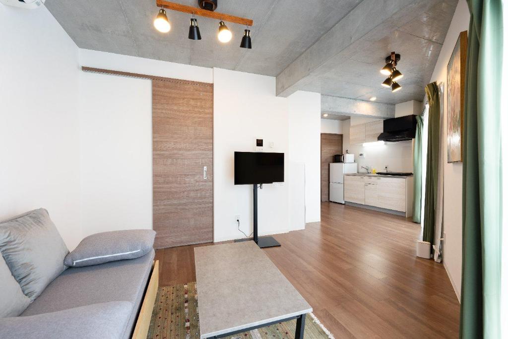 een woonkamer met een bank en een flatscreen-tv bij JASPER Waseda in Tokyo