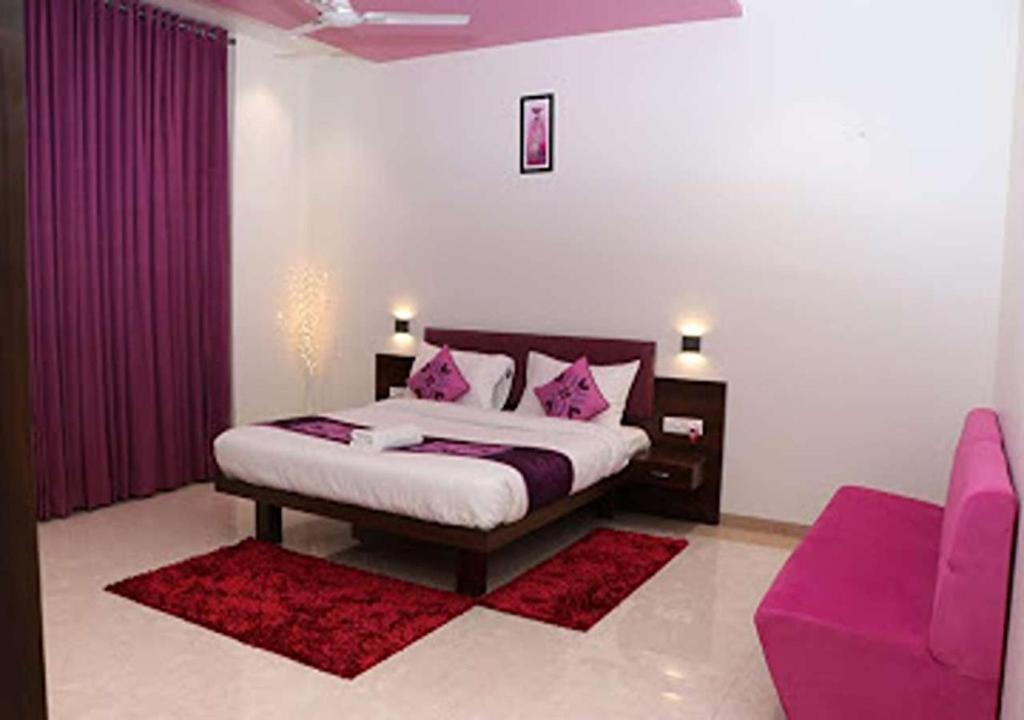ナンデッドにあるHOTEL CVRのベッドルーム1室(ピンクの枕と紫色のソファ付きのベッド1台付)