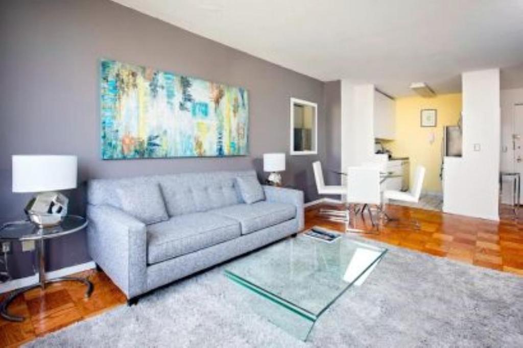 ein Wohnzimmer mit einem Sofa und einem Glastisch in der Unterkunft Beautiful 3 BR Apartment in Manhattan in New York