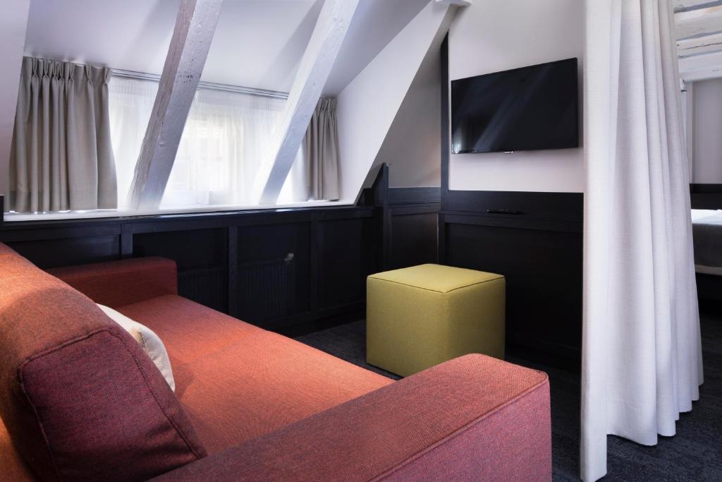 a living room with a couch and a tv at Hôtel Du Dragon in Strasbourg