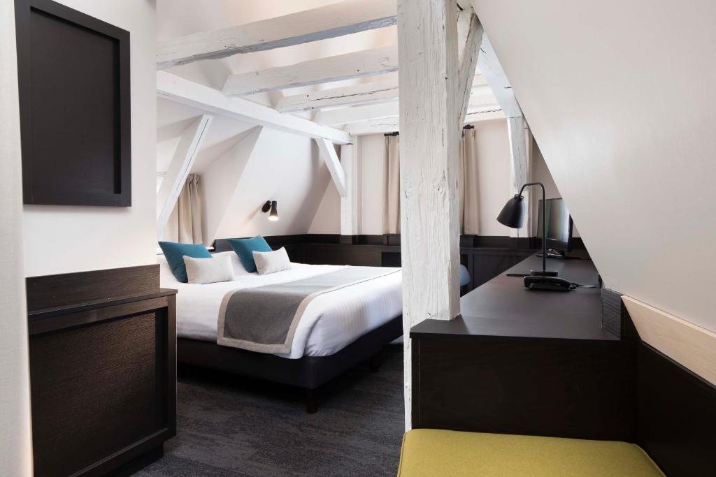 a hotel room with a bed and a tv at Hôtel Du Dragon in Strasbourg