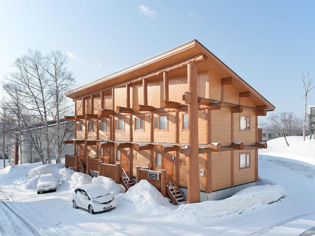 a wooden house with two cars parked in the snow at Silver Birch in Niseko