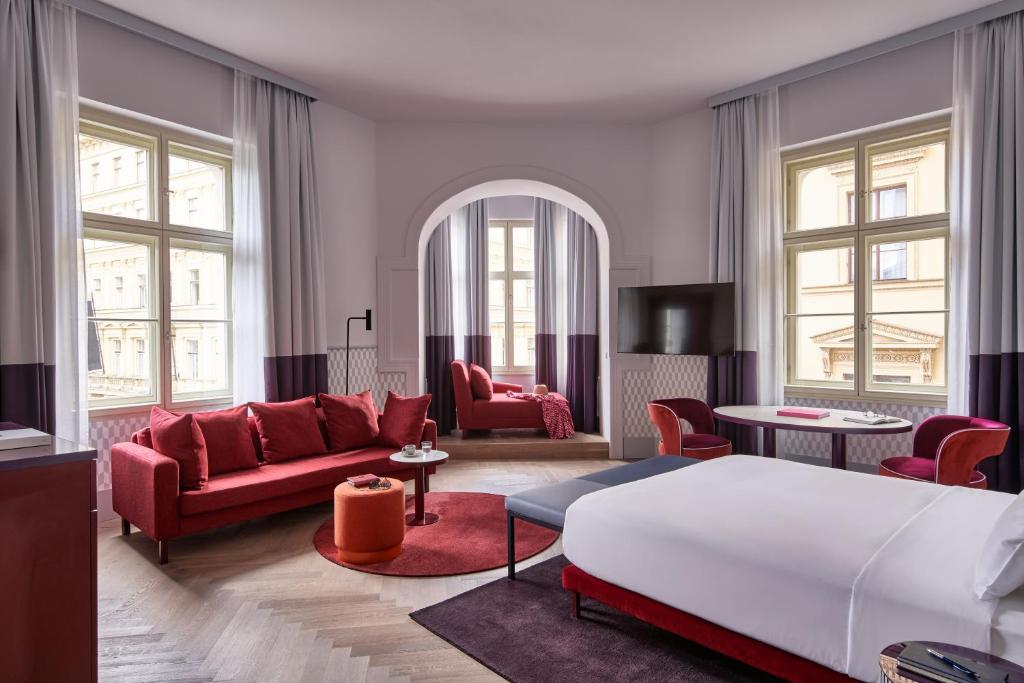 a living room with red furniture and a bed at Falkensteiner Boutique Hotel Prague in Prague