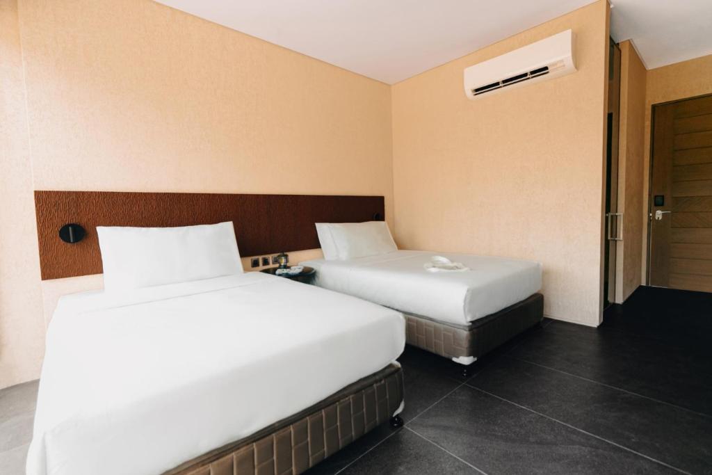 a hotel room with two beds and a door at The Funny Lion - Puerto Princesa in Puerto Princesa City