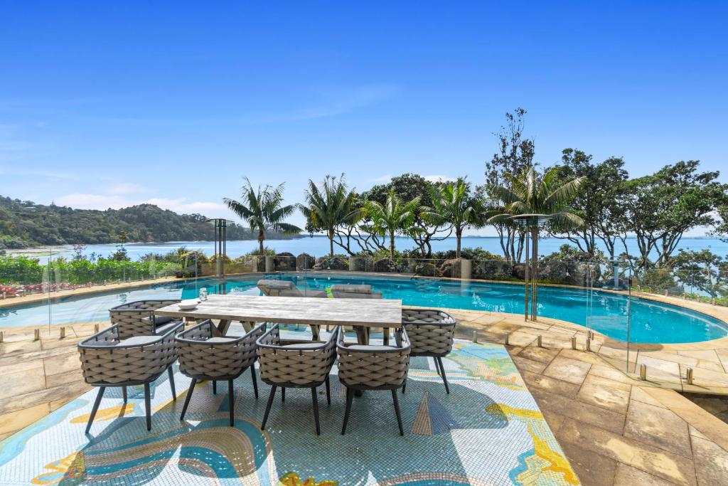 a table and chairs next to a swimming pool at Beachside Luxury - Laingholm Holiday Apartment in Titirangi