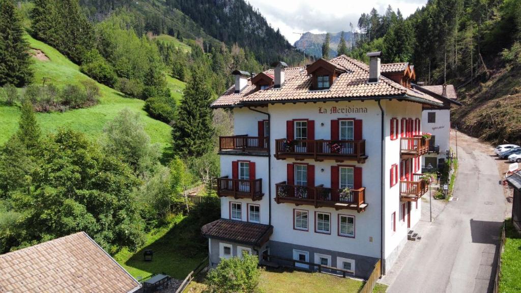 a large white building with balconies on a mountain at Dolomites Hotel La Meridiana in Moena