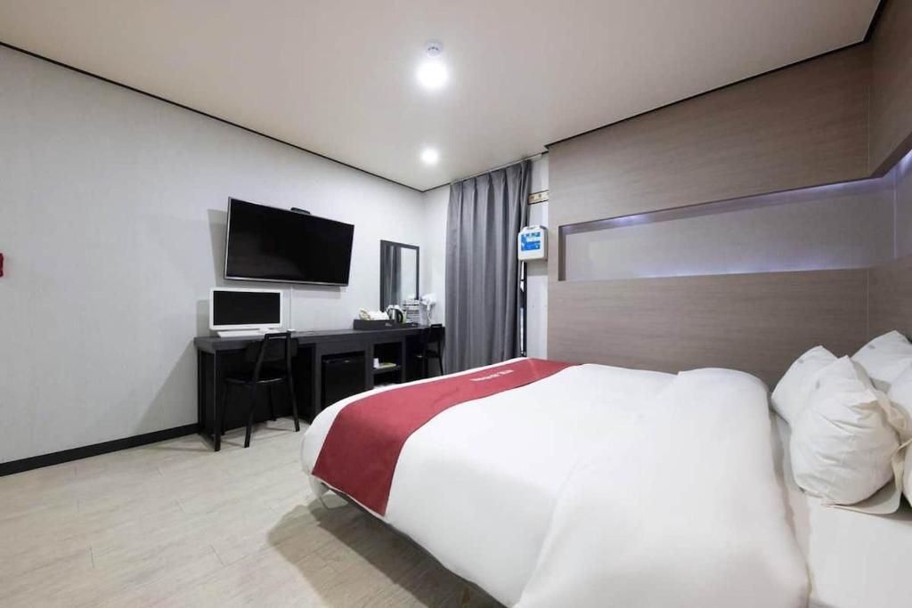 Seosan Hotel November في Seosan: غرفة نوم بسرير ومكتب مع تلفزيون
