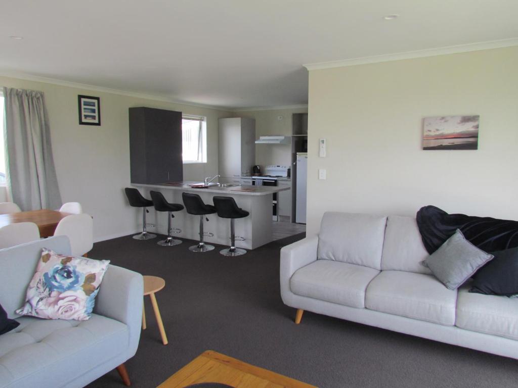 a living room with two couches and a kitchen at West Coast Wonder 4 Minutes Drive to Glinks Gully in Te Kopuru