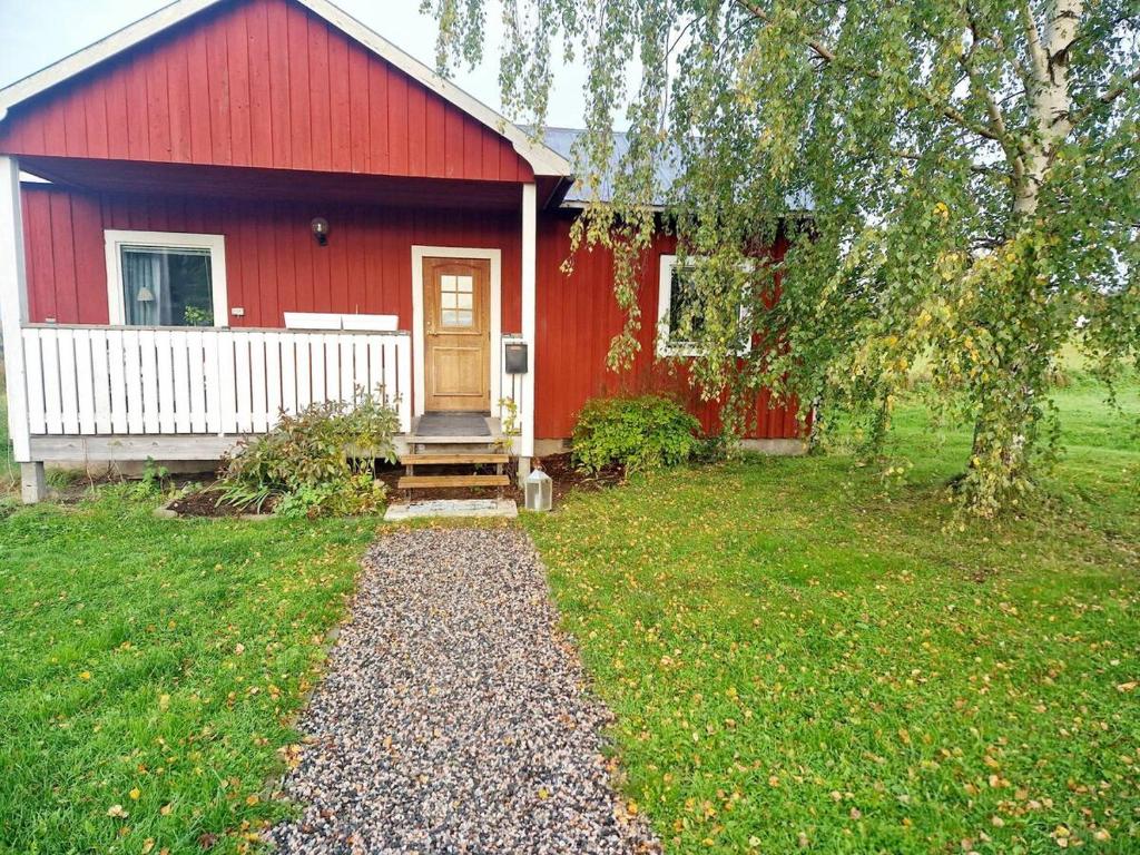 una casa roja con un camino delante de ella en Litet hus på gård med utsikt över indalsälven, en Indal