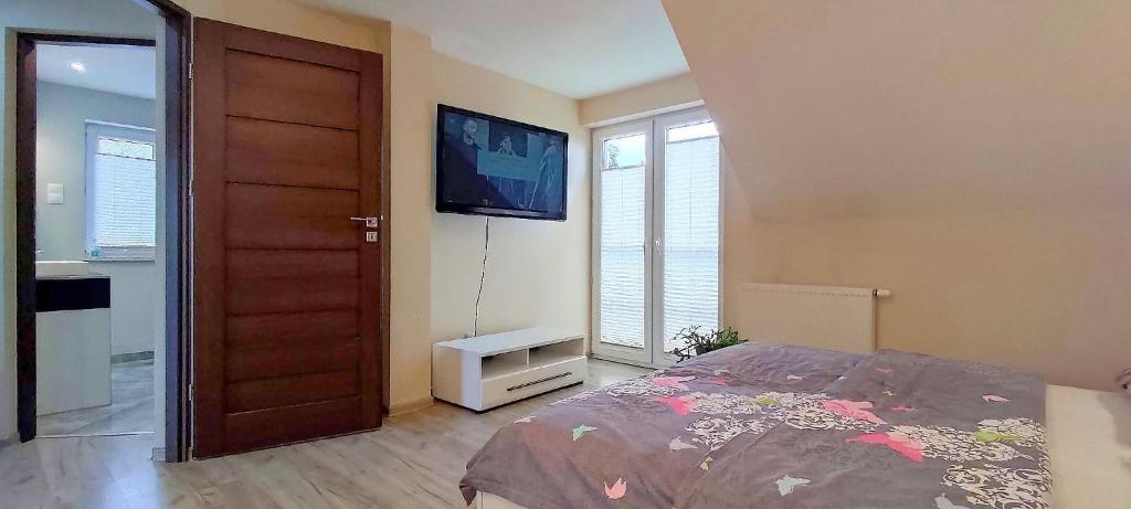 um quarto com uma cama e uma televisão de ecrã plano em Waldi Apartament Cieplice em Jelenia Góra